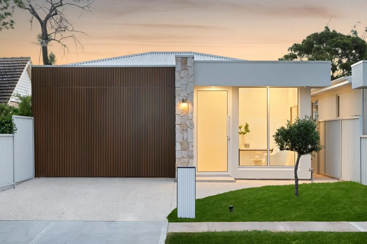 Home with batten garage door and stone pillar at sunset