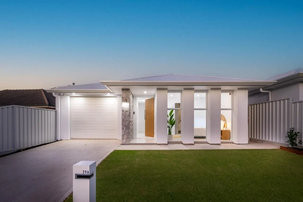 Single-storey home with stone entry and timber door at dusk