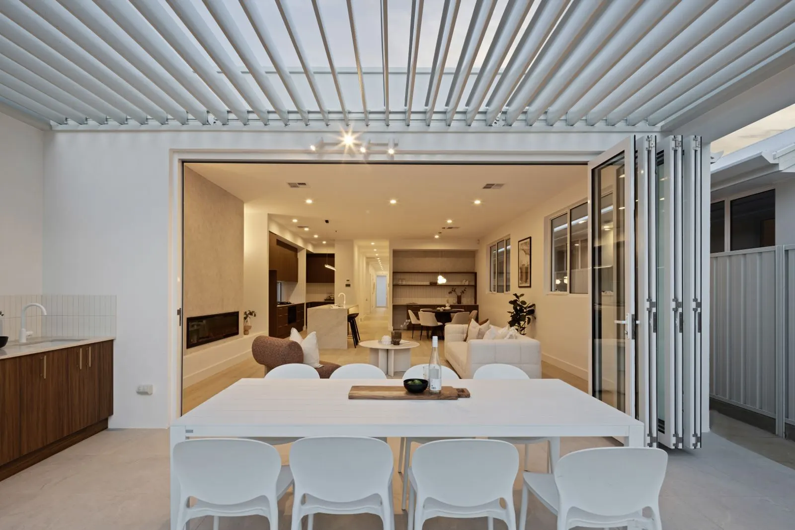 Louvred alfresco opening onto open-plan living at dusk