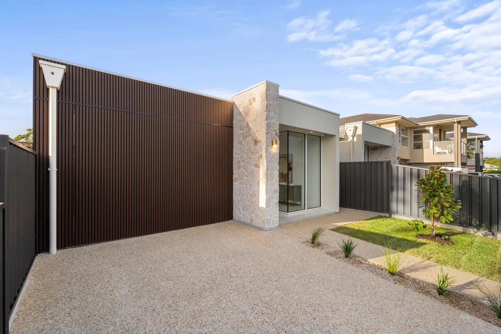 Stone-clad entry beside a timber-look garage door