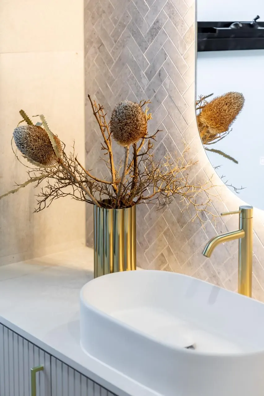 Bathroom vanity with brass tapware and herringbone tiles