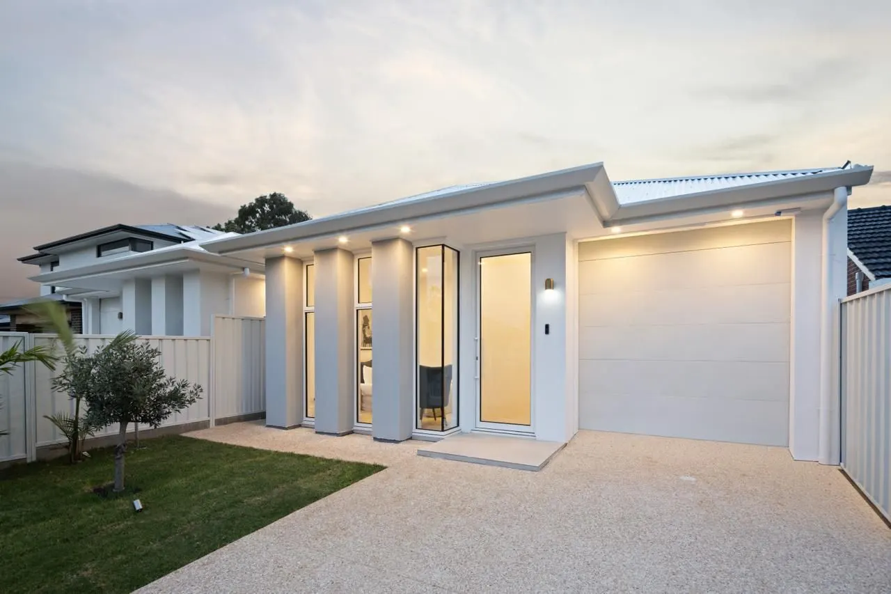 White single-storey home with glazed entry at dusk